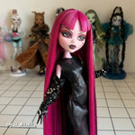 Front-facing waist-up custom reroot example of Cerise Pink saran doll hair on Monster High Draculaura by @thedolldaddie. Detailed shot featuring straight waist-length hair with blunt bangs and black lowlights, paired with a black faux-leather outfit and studded gloves.
