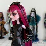 Side profile close-up custom reroot example of Cerise Pink saran doll hair on Monster High Draculaura by @thedolldaddie. Highlight shot showing the sleek hair texture, blunt bangs with black streak accents, and black sunglasses resting on top of the head.