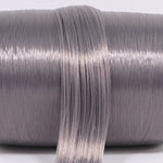 A hank of eclipse gray nylon doll hair laying across a roll. The dark gray has a subtle purple/violet hue for one of a kind custom reroots.