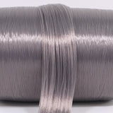 A hank of eclipse gray nylon doll hair laying across a roll. The dark gray has a subtle purple/violet hue for one of a kind custom reroots.