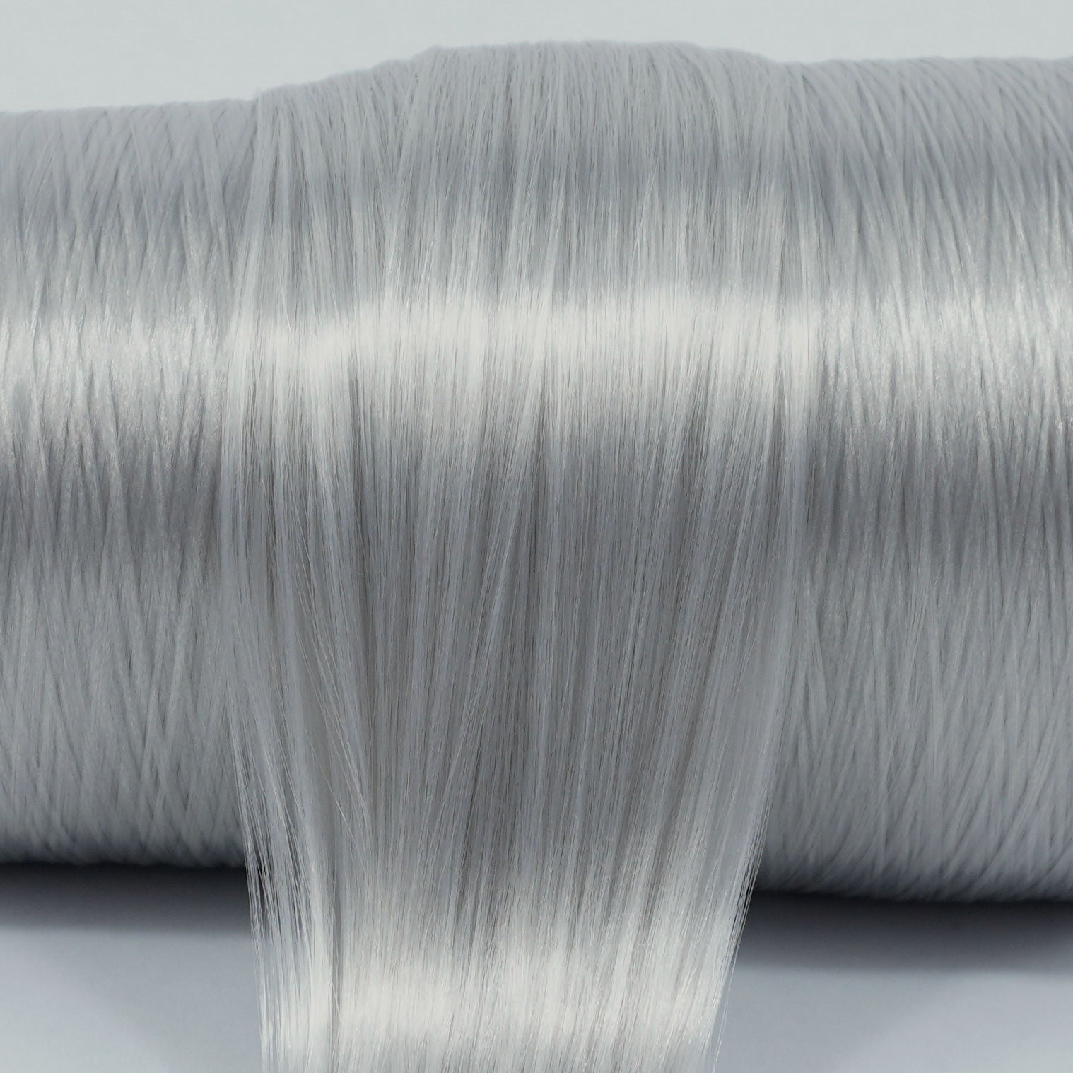 Granite Gray nylon doll hair spool by Shimmer Locks. Smooth, cool-toned stone gray fiber showing shine and texture on the roll