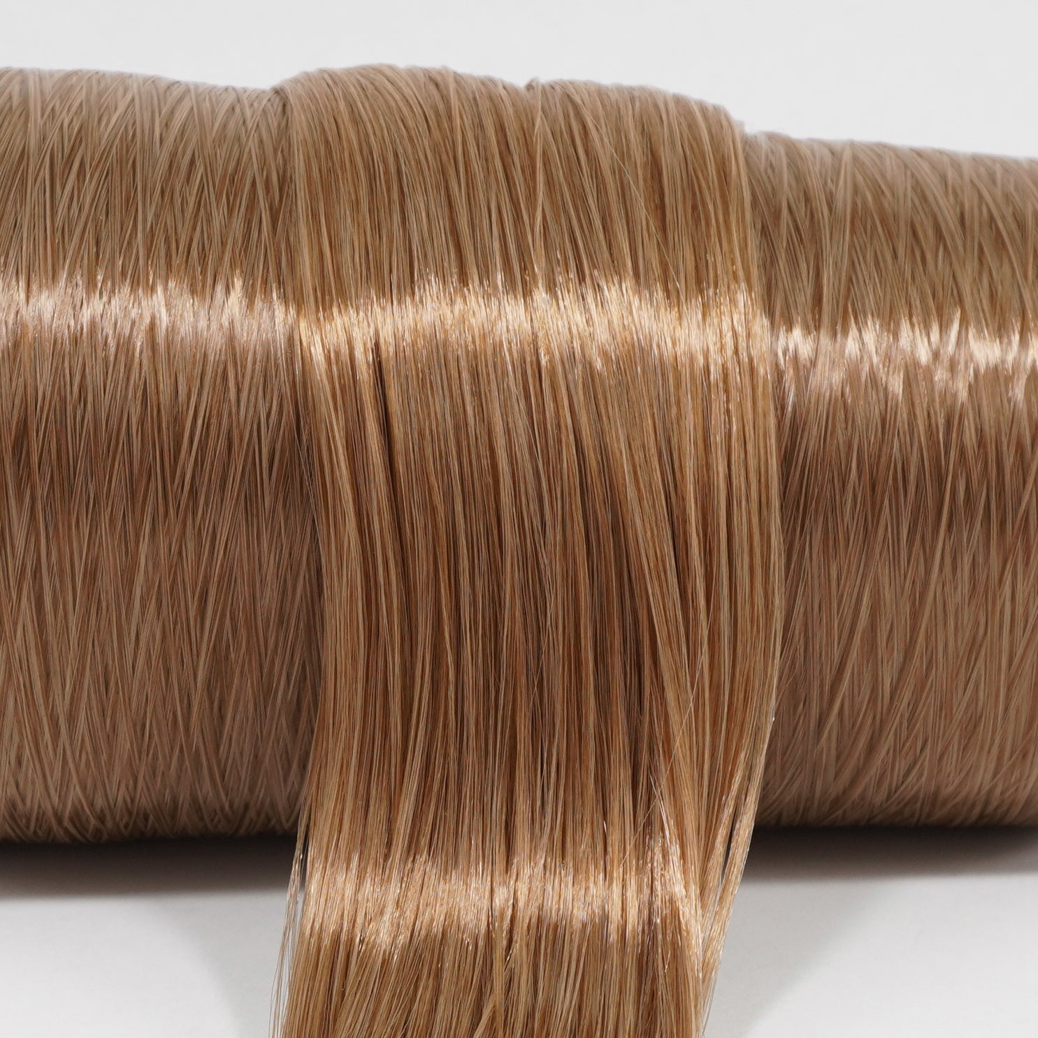 Iced Latte brown nylon doll hair spool showing the smooth texture and shine of the two-tone fiber on the roll