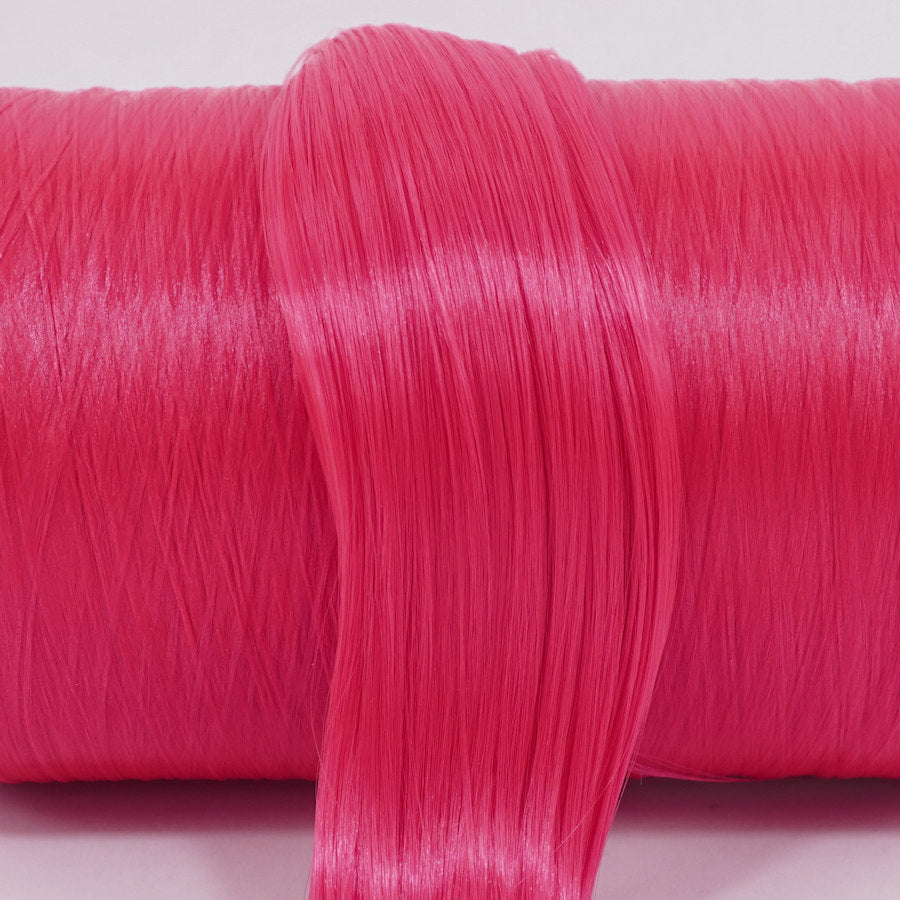 Pizzazz hot pink nylon doll hair hank for rerooting laying across a roll of the same color.