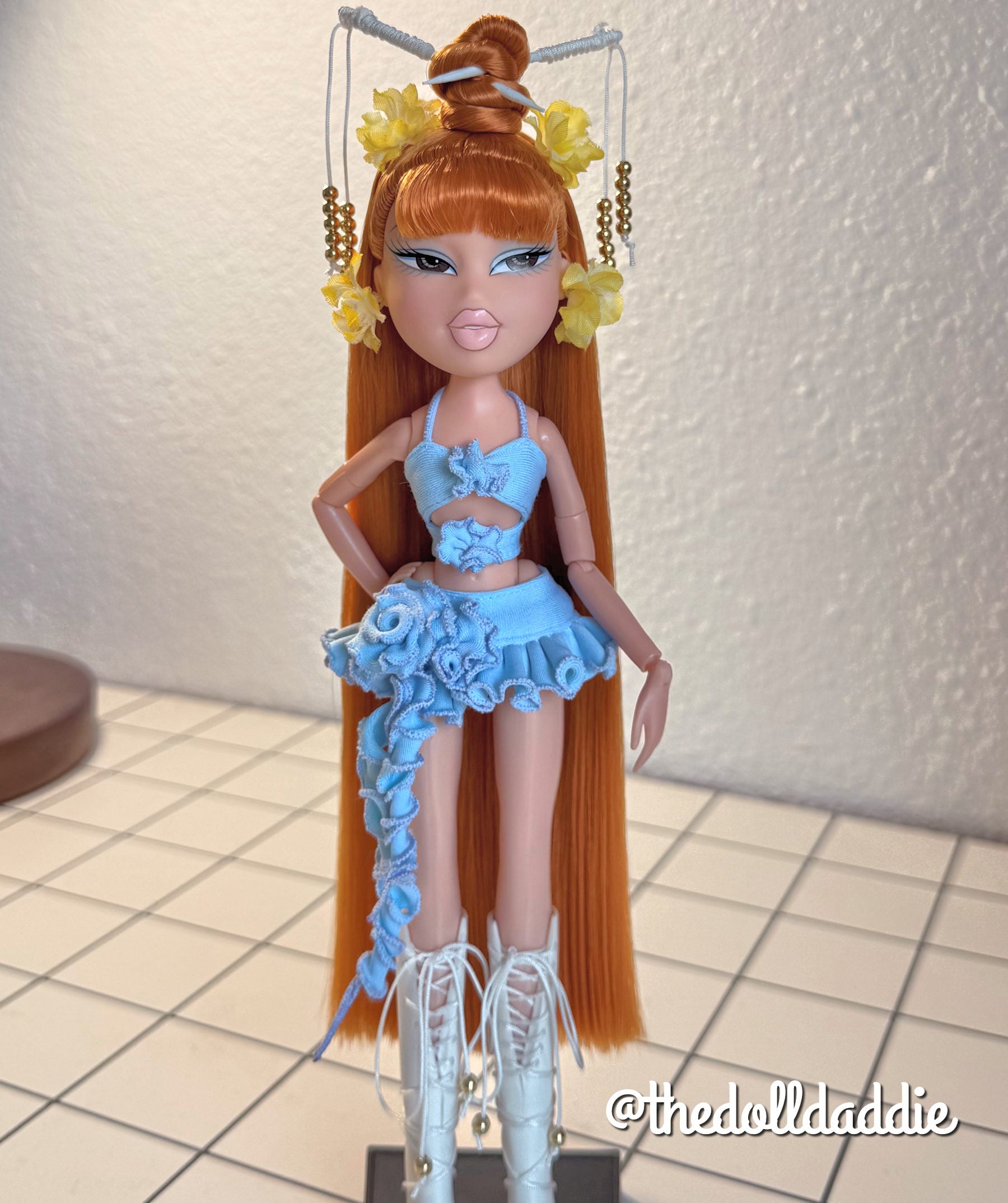 Full-length custom reroot example of Safari Auburn saran doll hair on Bratz Pop Starz Jade by @thedolldaddie. Full shot displaying the waist-length straight hair, styled topknot bun, blunt bangs, and light blue outfit.
