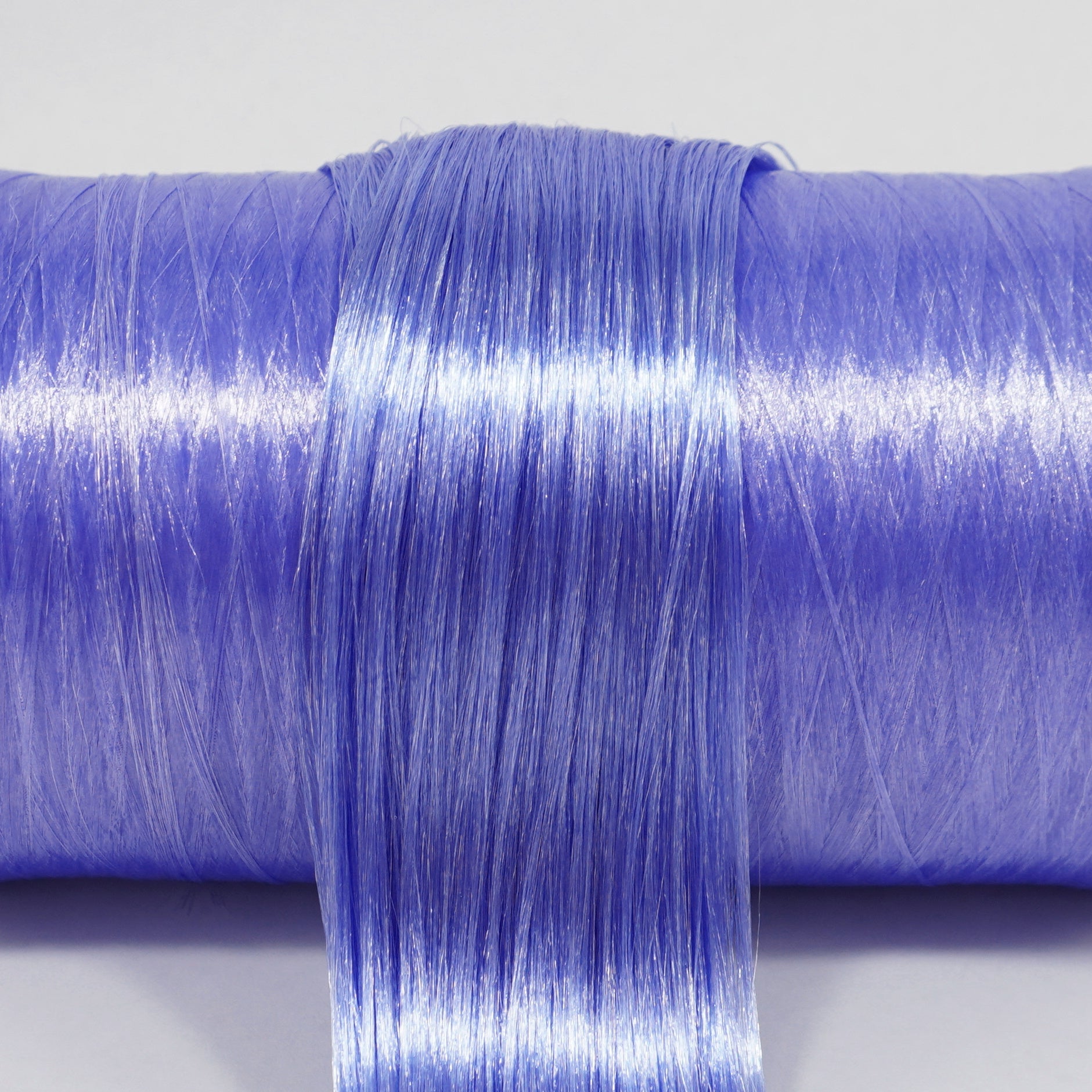 Metallic Supernova nylon doll hair spool by Shimmer Locks. Smooth, metallic indigo-violet fiber showing high-shine celestial texture on the roll.